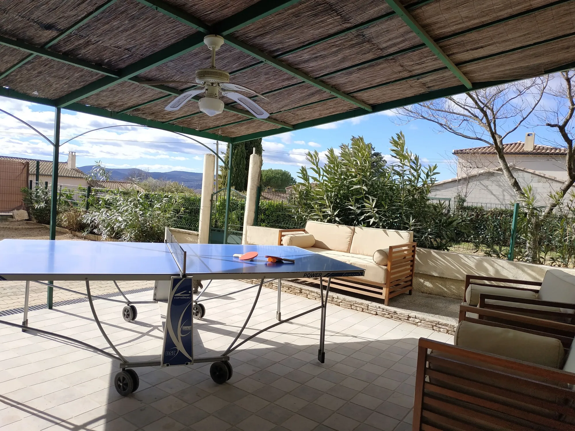 Le patio couvert d'une canisse, avec la table de ping-pong et un canapé d'extérieur