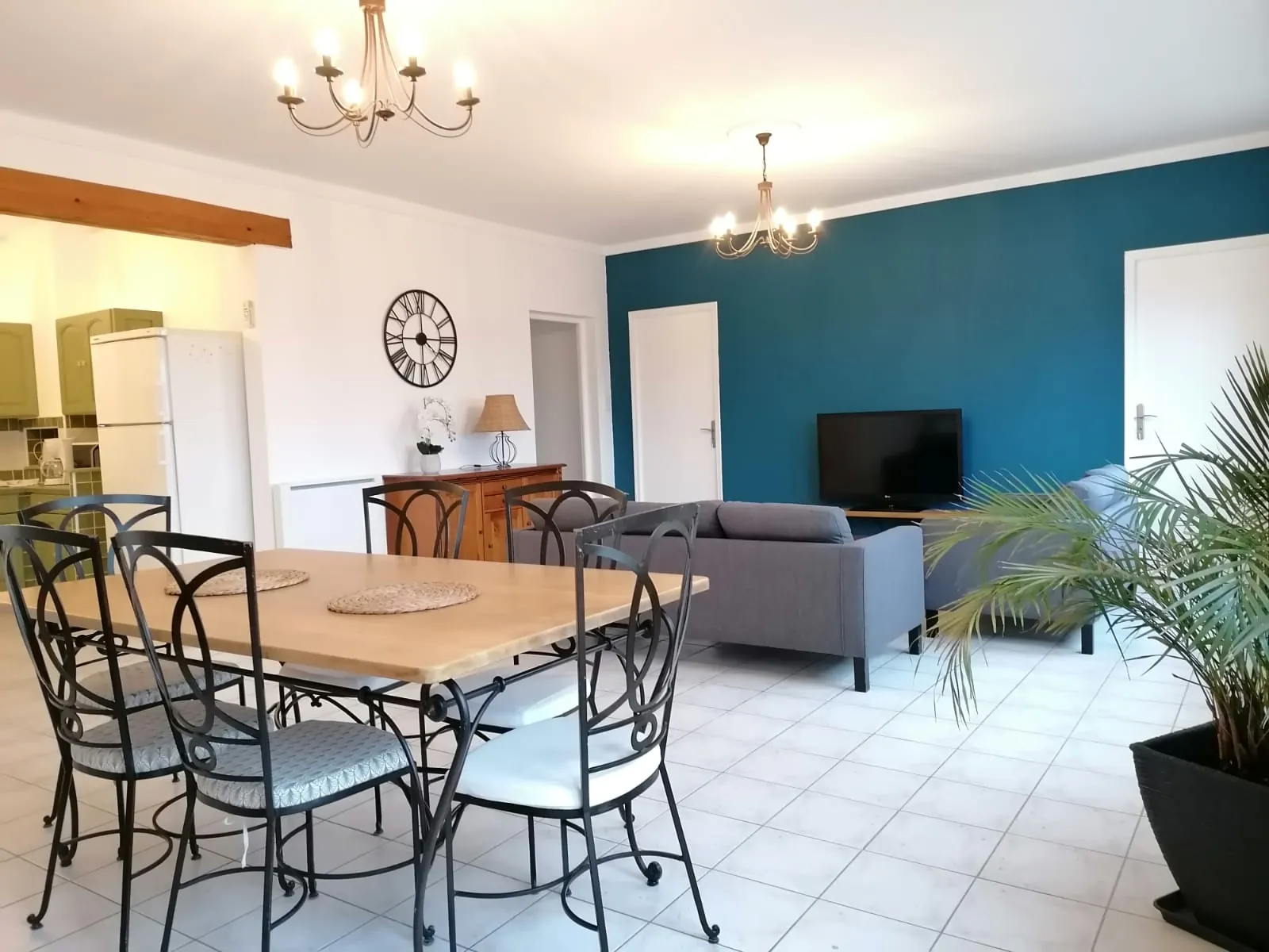 La pièce de vie : table à manger pour six, canapé, télévision et cuisine ouverte au fond