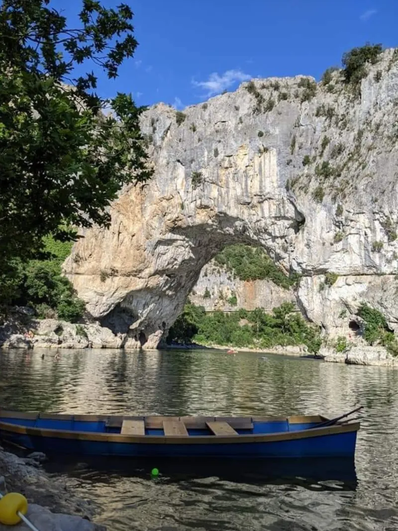 L'arche naturelle du Pont d'Arc au-dessus de la rivière Ardèche, avec une barque au premier plan