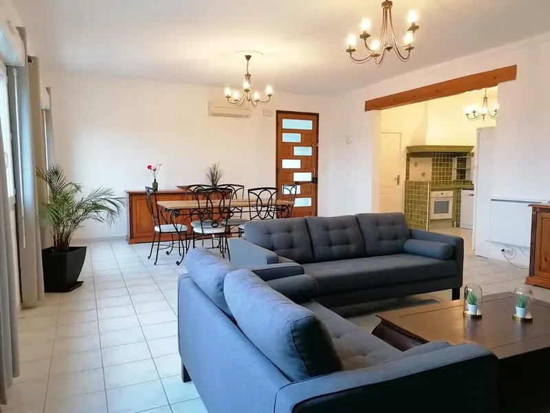 Deux canapés en angle autour d'une table basse, avec la salle à manger derrière